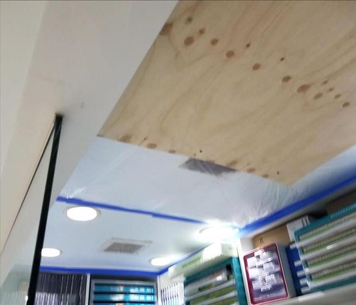 Photo is showing a ceiling tile boarded up with wood due to a break-in in this commercial building