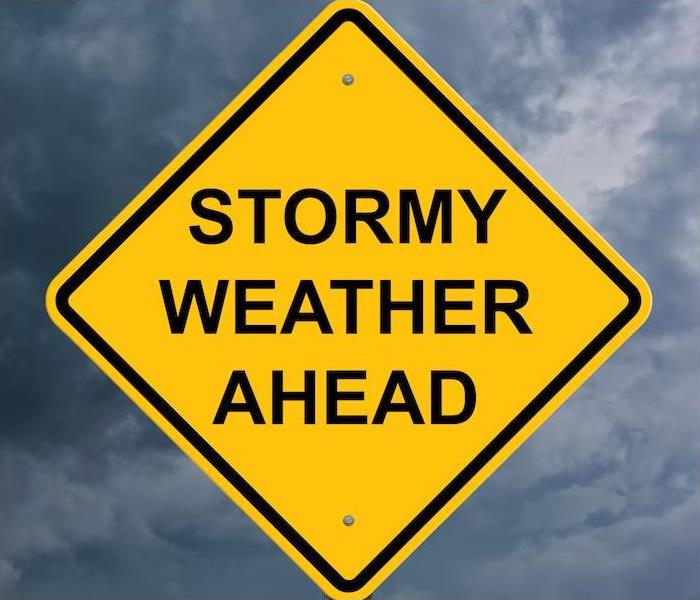 Photo is showing a yellow street sign saying Stormy Weather Ahead