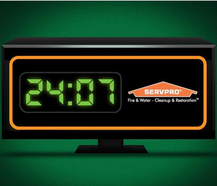A black alarm clock with an orange border around the edges. The time is set to 24:07 and a SERVPRO house logo to the right.